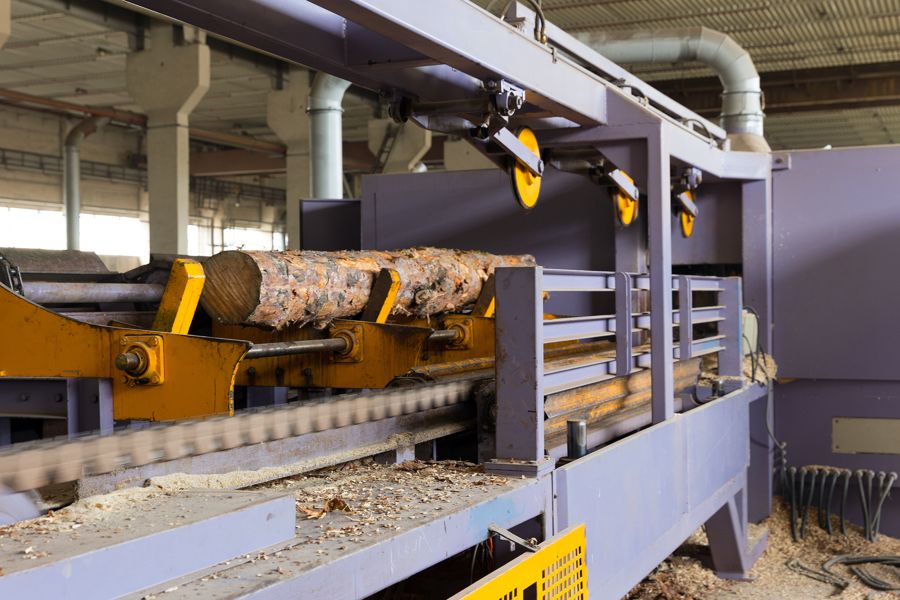 Log being fed along a chain conveyor with yellow rollers